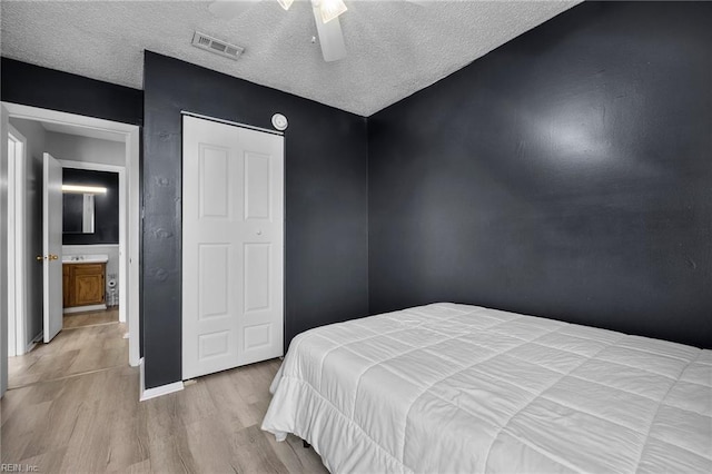 bedroom with visible vents, a ceiling fan, a textured ceiling, wood finished floors, and baseboards