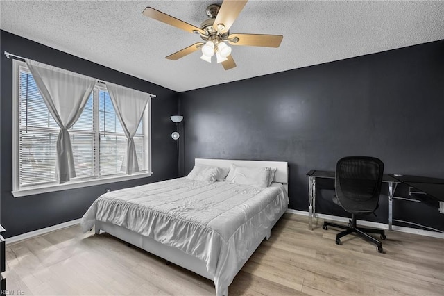 bedroom featuring an accent wall, wood finished floors, baseboards, and a textured ceiling