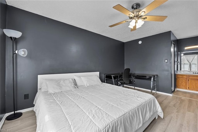 bedroom with baseboards, a textured ceiling, and light wood-style flooring