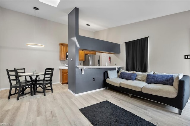 living area with baseboards, light wood-style flooring, and a towering ceiling