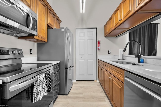 kitchen with a sink, stainless steel appliances, brown cabinets, and light countertops