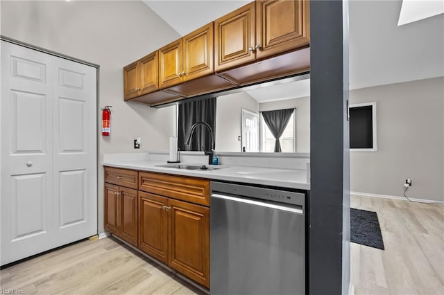 kitchen featuring brown cabinets, dishwasher, light countertops, and a sink