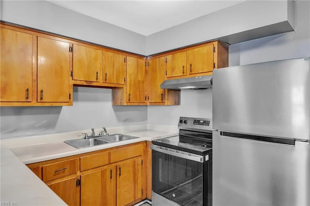 kitchen with under cabinet range hood, light countertops, appliances with stainless steel finishes, brown cabinetry, and a sink