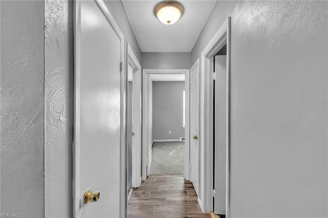 hall with wood finish floors and a textured wall