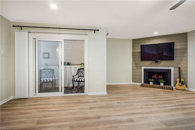 unfurnished living room featuring wood finished floors, recessed lighting, a fireplace, baseboards, and ceiling fan