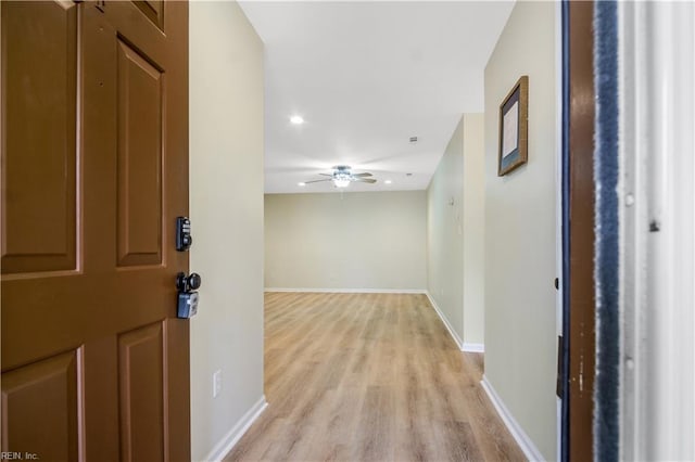 hallway with recessed lighting, light wood-style floors, and baseboards