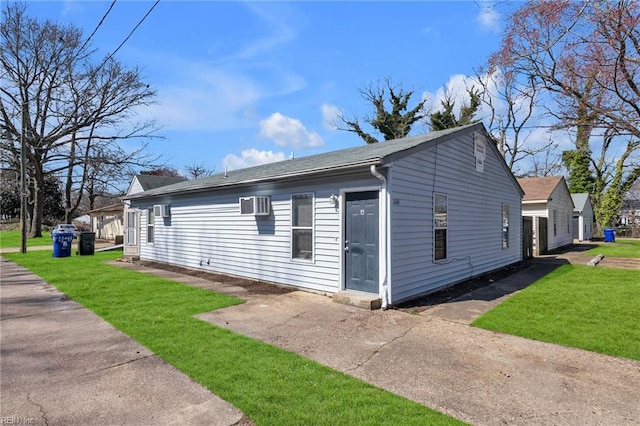 view of side of property featuring a yard and a wall mounted AC