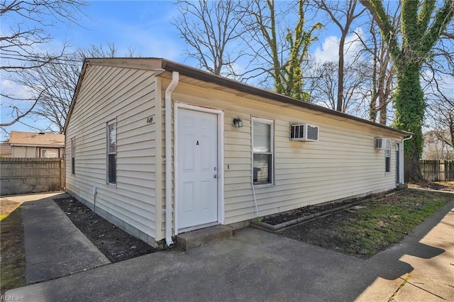 view of outbuilding with a wall mounted air conditioner and fence