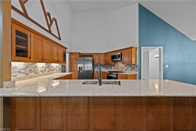 kitchen featuring a sink, brown cabinetry, glass insert cabinets, and stainless steel appliances