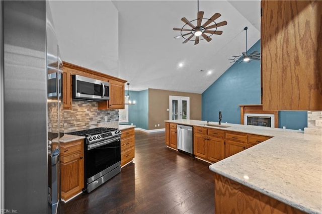 kitchen featuring ceiling fan, dark wood finished floors, brown cabinets, appliances with stainless steel finishes, and a sink