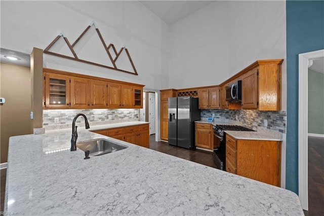 kitchen with a sink, stainless steel appliances, brown cabinets, and glass insert cabinets