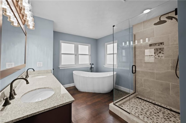 bathroom featuring a shower stall, a freestanding tub, double vanity, and a sink