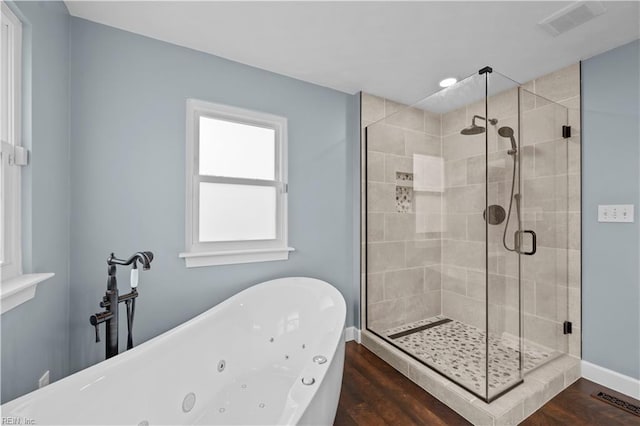 bathroom featuring visible vents, a stall shower, wood finished floors, baseboards, and a soaking tub