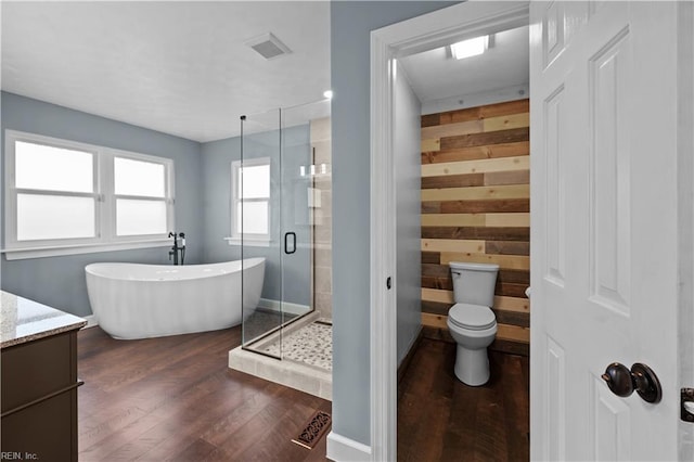 full bath with wood finished floors, visible vents, a soaking tub, a shower stall, and toilet