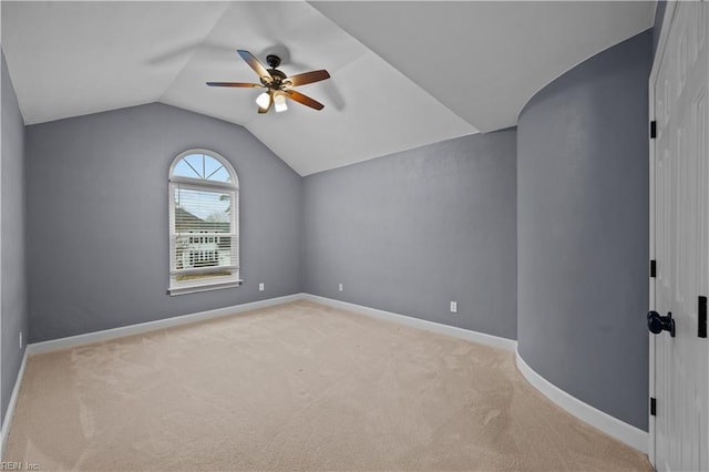 spare room featuring lofted ceiling, light carpet, baseboards, and ceiling fan