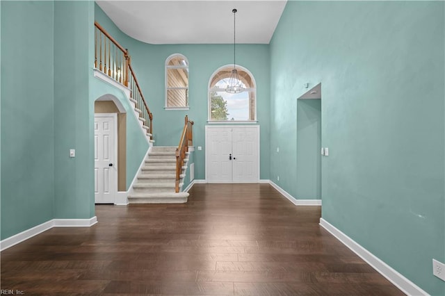 entryway with baseboards, stairs, an inviting chandelier, wood finished floors, and arched walkways