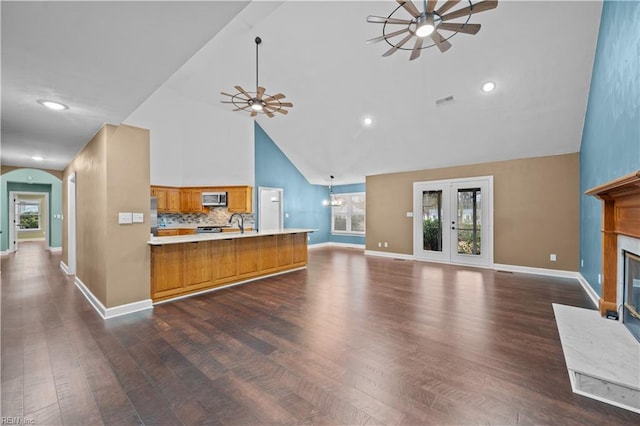 kitchen featuring stainless steel microwave, brown cabinetry, open floor plan, and ceiling fan