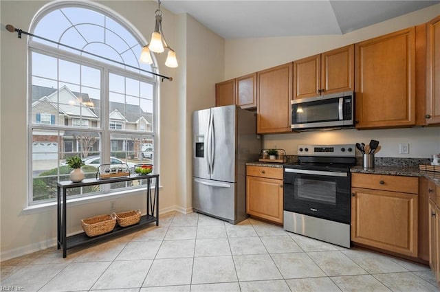 kitchen featuring decorative light fixtures, lofted ceiling, light tile patterned floors, appliances with stainless steel finishes, and brown cabinetry