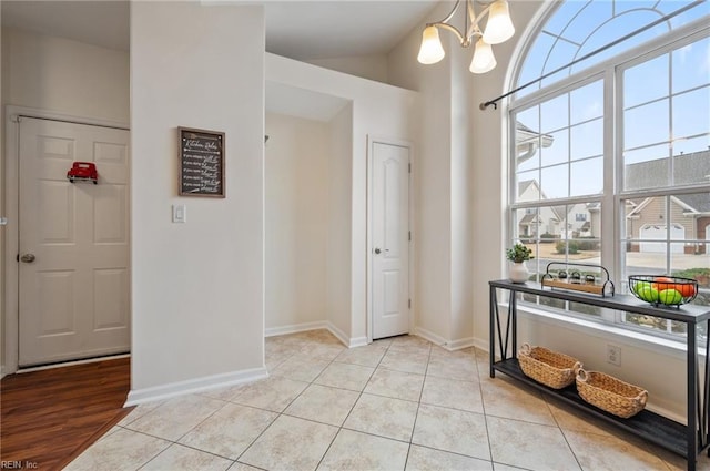 foyer entrance with a wealth of natural light, baseboards, a notable chandelier, and light tile patterned floors