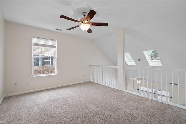 bonus room featuring visible vents, lofted ceiling with skylight, carpet flooring, baseboards, and ceiling fan