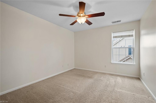 carpeted empty room with visible vents, baseboards, and a ceiling fan