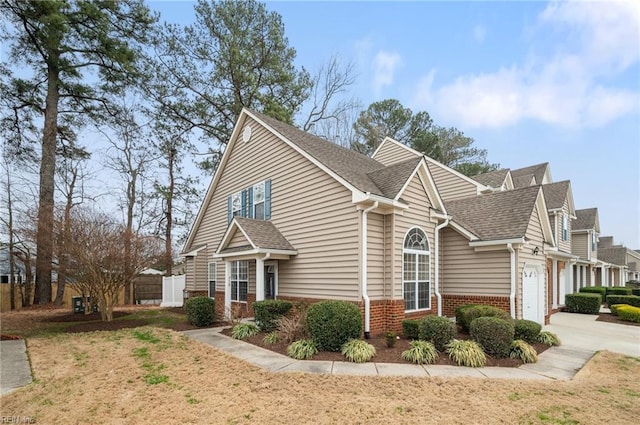 view of home's exterior featuring brick siding, a shingled roof, fence, concrete driveway, and an attached garage