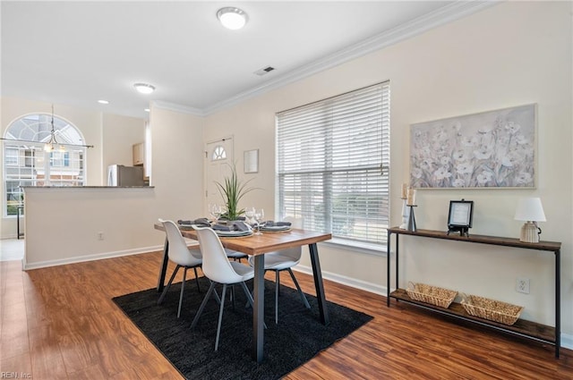 dining area featuring visible vents, baseboards, wood finished floors, and crown molding