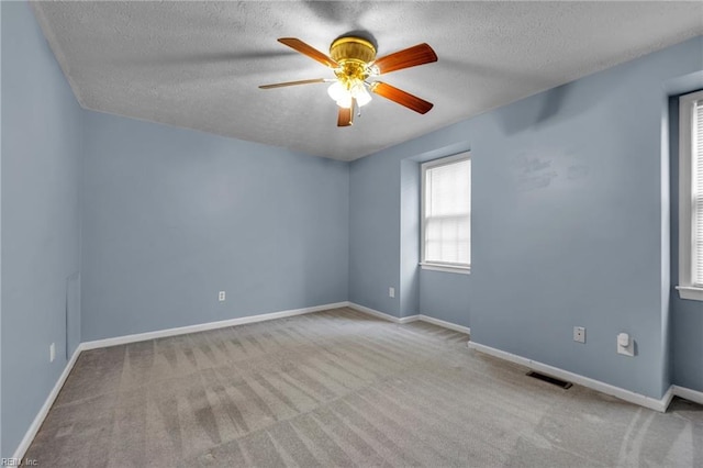 spare room with baseboards, visible vents, ceiling fan, a textured ceiling, and carpet flooring