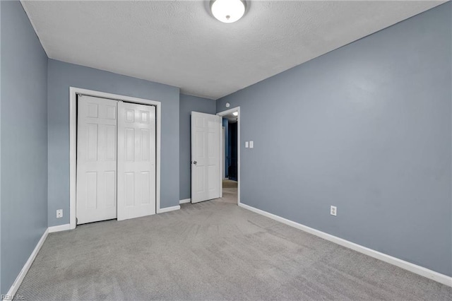 unfurnished bedroom featuring a closet, baseboards, a textured ceiling, and carpet flooring