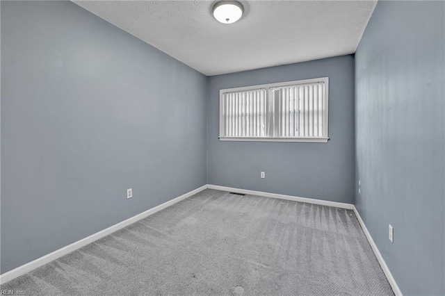 carpeted empty room with a textured ceiling and baseboards