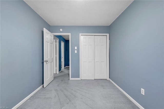 unfurnished bedroom featuring a closet, baseboards, carpet floors, and a textured ceiling