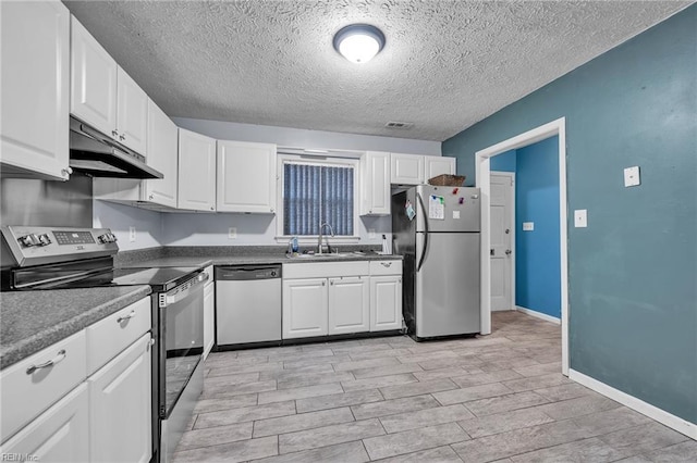 kitchen with under cabinet range hood, appliances with stainless steel finishes, white cabinetry, and a sink