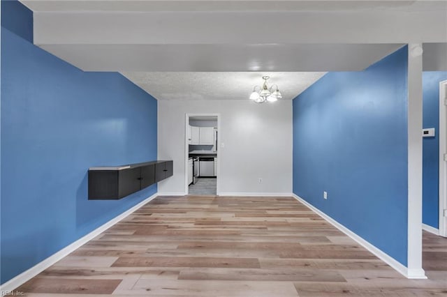 interior space featuring light wood-style flooring, a notable chandelier, and baseboards