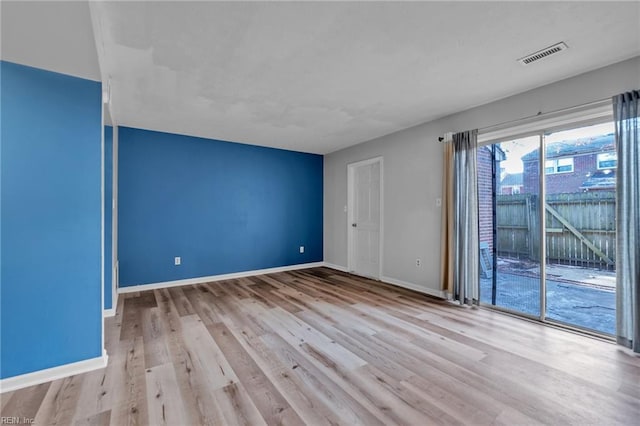 unfurnished room featuring visible vents, baseboards, and wood finished floors