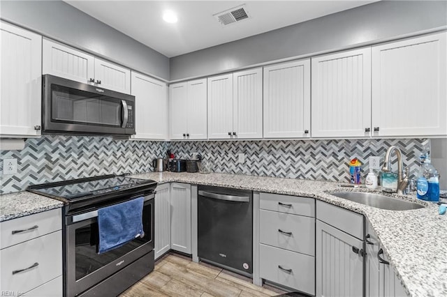 kitchen featuring dishwashing machine, visible vents, light wood finished floors, stainless steel electric stove, and a sink