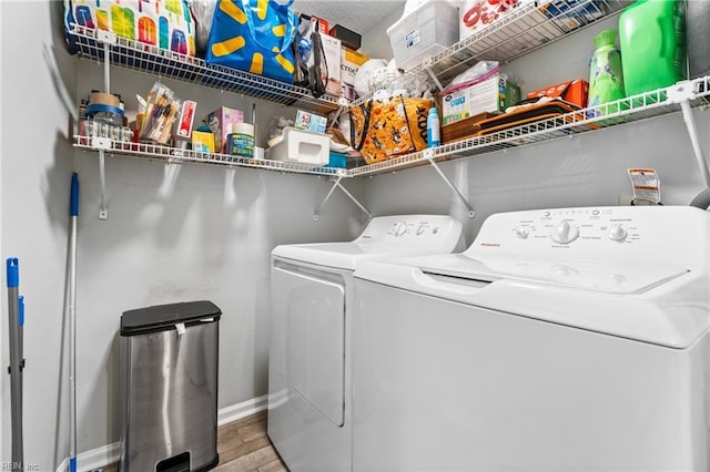 clothes washing area with washing machine and clothes dryer, laundry area, baseboards, and wood finished floors