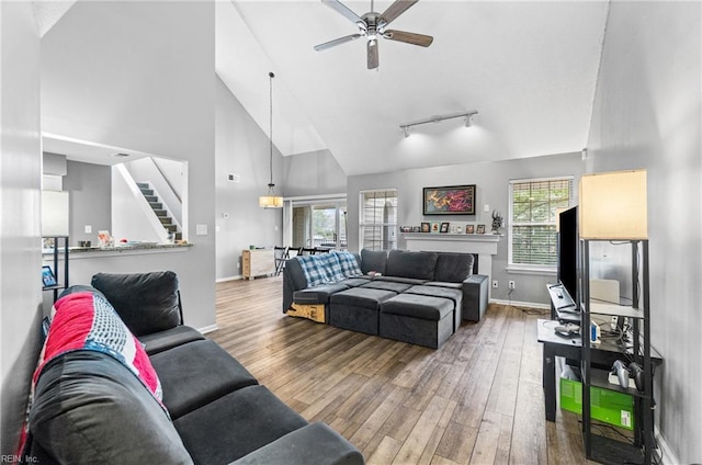 living room with baseboards, stairs, wood finished floors, high vaulted ceiling, and a ceiling fan