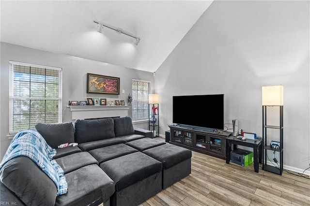 living area featuring track lighting, plenty of natural light, light wood-style floors, and baseboards