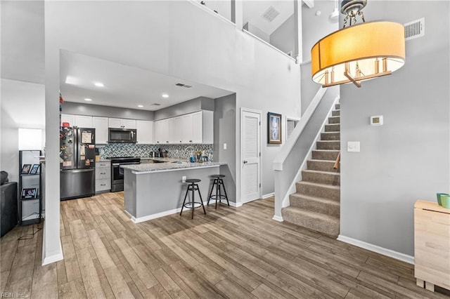 kitchen featuring tasteful backsplash, white cabinets, appliances with stainless steel finishes, and light wood-style floors