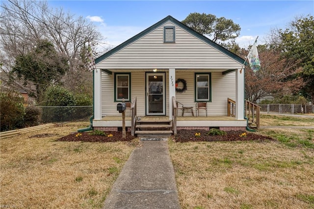 bungalow-style home featuring a front lawn, fence, and covered porch