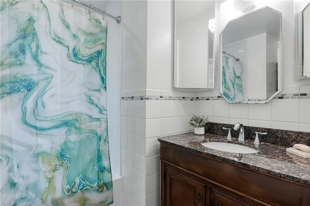 full bathroom with a shower with curtain, tile walls, and vanity