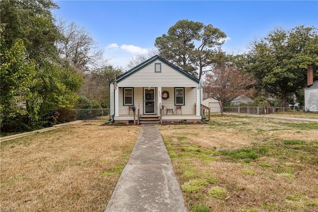 bungalow-style home featuring a front yard, fence, and covered porch