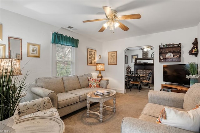 living area featuring visible vents, a ceiling fan, arched walkways, and carpet floors