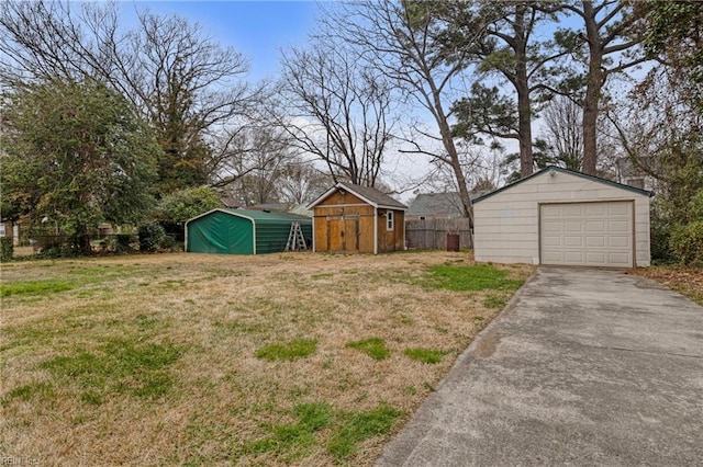 view of yard with a detached garage, driveway, a storage shed, and an outdoor structure