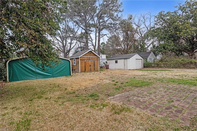 view of yard with a garage, an outbuilding, and a storage shed