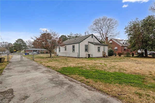 view of side of property featuring concrete driveway, a gate, fence, and a yard