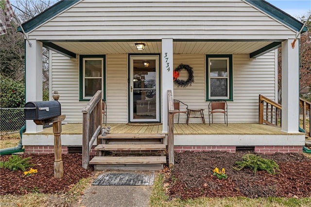 doorway to property featuring a porch and fence