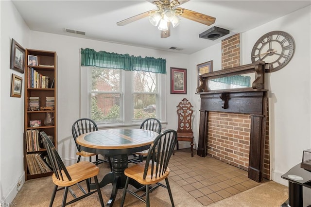 dining space featuring visible vents, baseboards, a fireplace, and a ceiling fan