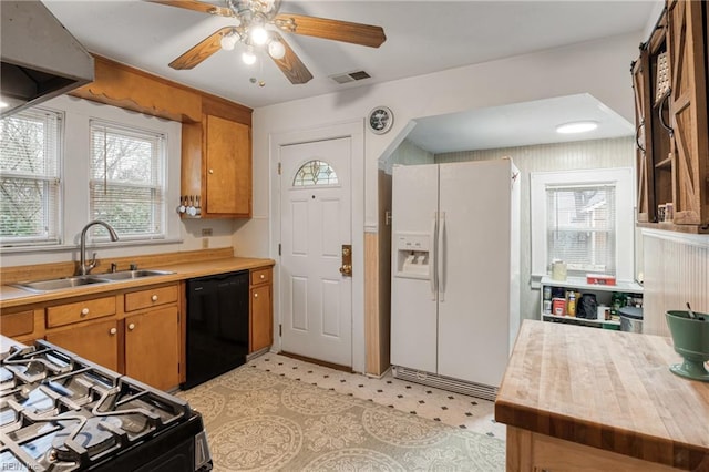 kitchen featuring visible vents, brown cabinets, black appliances, a sink, and light countertops