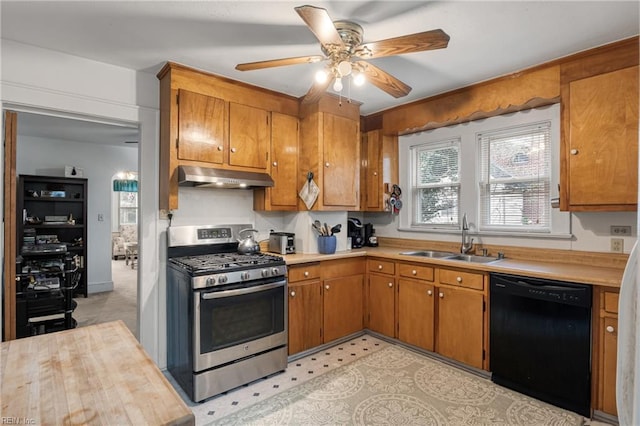 kitchen with stainless steel gas range oven, under cabinet range hood, light countertops, black dishwasher, and a sink